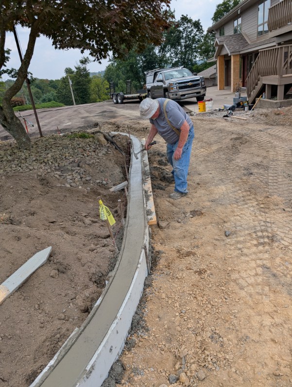 Crew member finishing a freshly poured curved concrete curb in Allegheny County, PA