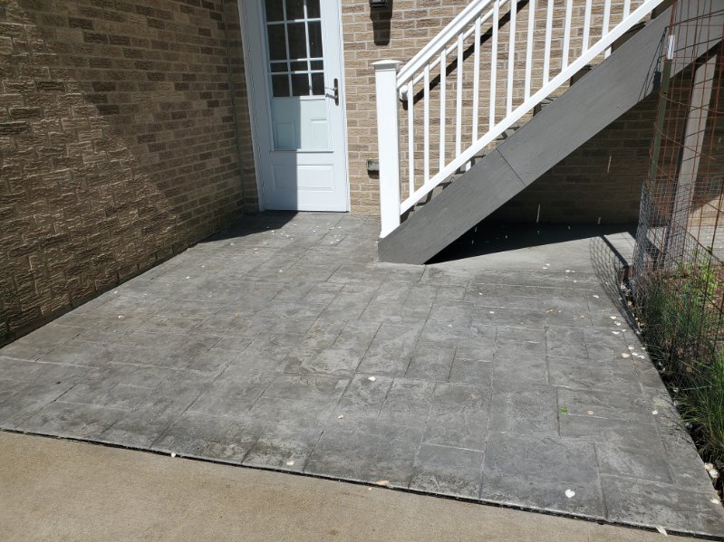 Charcoal ashlar stamped concrete patio beside a brick home near Pittsburgh, PA