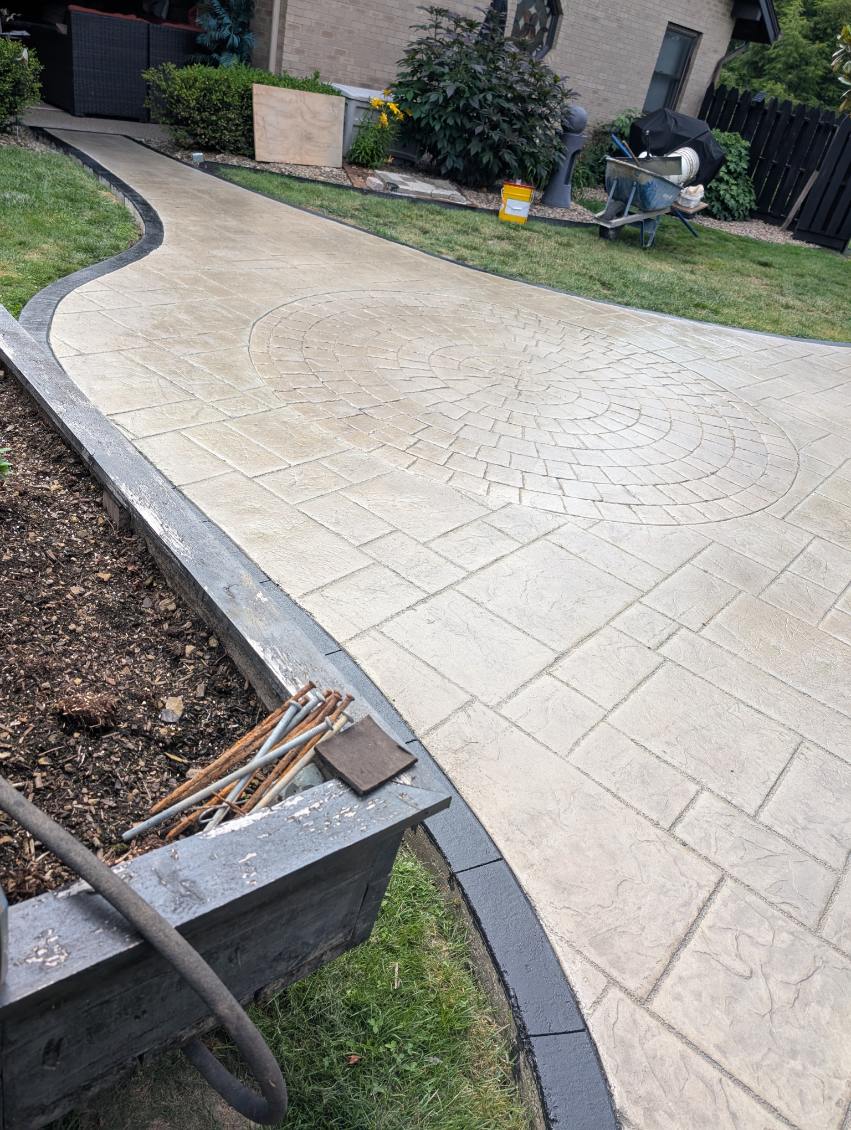 Stamped concrete patio with circular inlay pattern and charcoal border in the North Hills, PA
